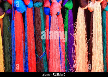 Set di filetti manycolored per la tessitura appeso all'esterno di un negozio in una strada del mercato nel 3840 ms.Shigatse-Tibet alta. Foto Stock