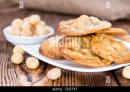 Biscotti con Noci Macadamia e il cioccolato bianco (su sfondo di legno) Foto Stock