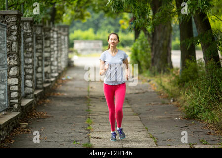 Pareggiatore di giovane ragazza che corre lungo il percorso nel parco. Foto Stock