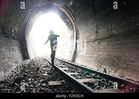 Bambino a piedi nella galleria ferroviaria. Abbigliamento vintage Foto Stock