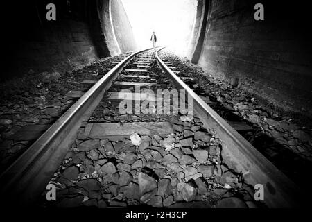 Bambino a piedi nella galleria ferroviaria. Abbigliamento vintage Foto Stock