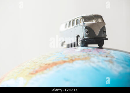 Vintage bus VW sul globo terrestre. Concetto in miniatura Foto Stock