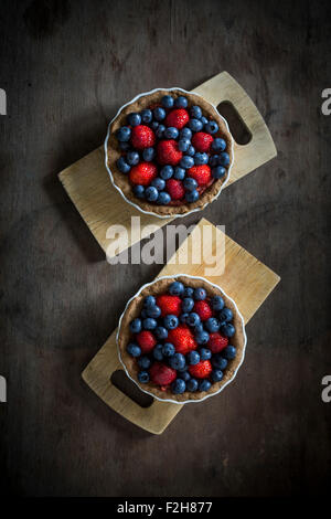 Berry tartetelets in piatti di cottura su piastre di legno. Vista superiore Foto Stock