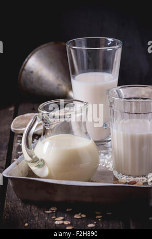 Set di non-latte (latte di riso, latte di mandorla e Latte di avena) in bicchieri di vetro e la brocca sulla vecchia vaschetta di alluminio con grani di riso, avena fla Foto Stock