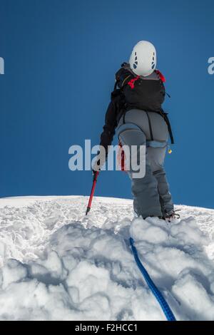 Scalatore femmina salendo un pendio nevoso. Foto Stock