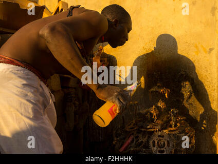 Il Benin, Africa Occidentale, Bonhicon, kagbanon bebe sacerdote voodoo di bere succo di arancia e sputare su ogun altare di Dio fatta con pedaliers bike Foto Stock