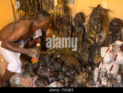 Il Benin, Africa Occidentale, Bonhicon, kagbanon bebe sacerdote voodoo di bere succo di arancia e sputare su ogun altare di Dio fatta con pedaliers bike Foto Stock