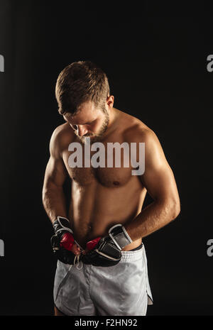 Athletic boxer barbuto con guanti su sfondo scuro Foto Stock