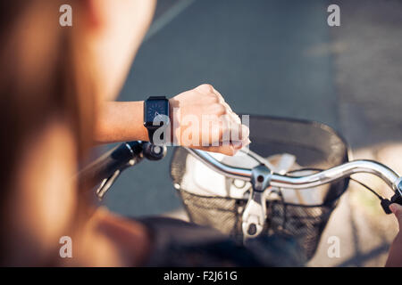La mano di una donna con smartwatch. Immagine ravvicinata di donna sulla bicicletta controllo ora sul suo smart orologio da polso. Foto Stock