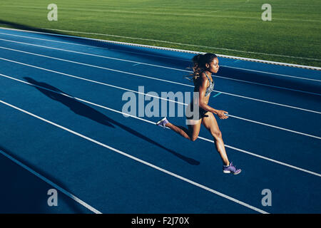 Colpo all'aperto della giovane donna africana atleta che corre sulla pista. Professional sportive durante l esecuzione di una sessione di formazione. Foto Stock