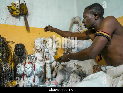 Il Benin, Africa Occidentale, Bonhicon, kagbanon bebe sacerdote voodoo di mettere un po' di olio sulle statue durante una cerimonia Foto Stock