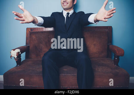 Happy businessman seduto sul divano con le sue braccia tese Foto Stock