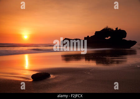 Tramonto mozzafiato a Yeh Gangga formazione rocciosa naturale su una spiaggia di Bali Foto Stock