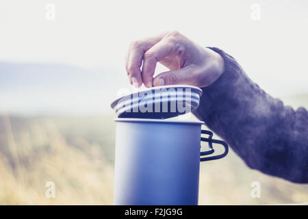 Donna che utilizza fornello da campeggio per bollire acqua al di fuori Foto Stock