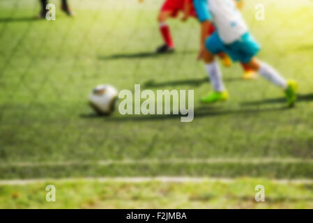 Ragazzi che giocano a calcio, utente malintenzionato esegue con sfera, defocussed blur sport immagine di sfondo Foto Stock