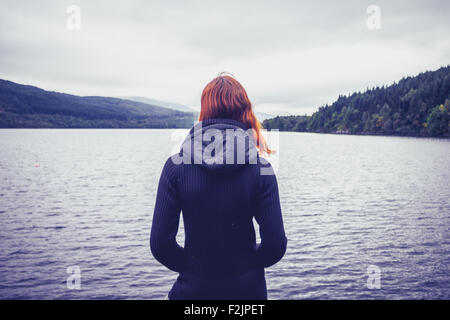 Giovane donna in piedi dal lago in autunno Foto Stock