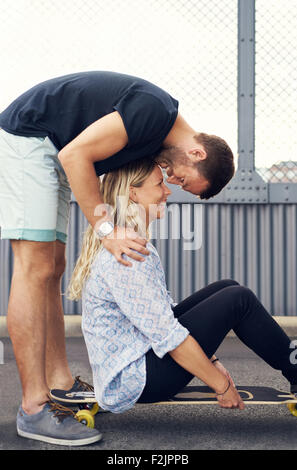 L'uomo sporgendoti donna bacia mentre sorride Foto Stock