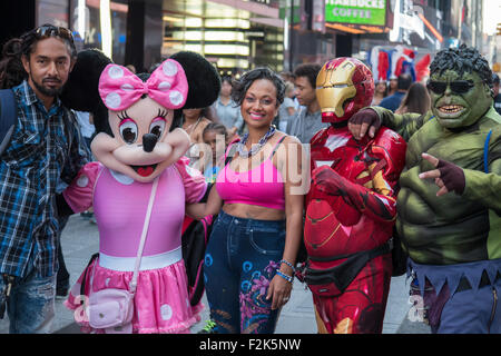 Un giovane pone per fotografie con artisti di strada vestiti come Minnie Mouse, uomo del ferro e la carcassa in Times Square a New York City. Foto Stock