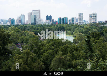 Parco Bosque de Chapultepec, Città del Messico | CITTÀ DEL MESSICO, Messico — Barche a remi colorate punteggiano il lago centrale del Bosque de Chapultepec mentre la fitta chioma degli alberi del parco incontra i grattacieli di Polanco oltre. Esteso su circa 1.695 acri (686 ettari), il bosco è uno dei più grandi parchi urbani dell'emisfero occidentale e ospita antiche querce ahuehuete (cipresso di Montezuma) piantate sotto il dominio azteco. La vista guarda verso nord dalla collina di Chapultepec, sito del castello del 1785 sopra. Foto Stock