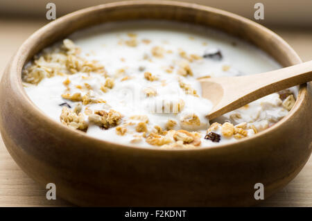 Muesli con frutta e latte in una ciotola di legno in stile rustico Foto Stock