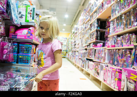 Bambino ragazza bionda scegliendo e shopping un giocattolo nel negozio di giocattoli Foto Stock