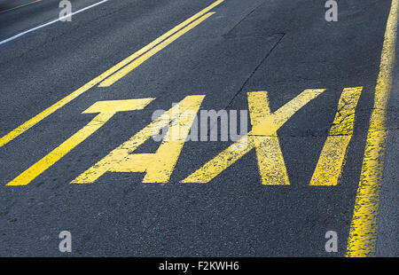 Giallo cartello stradale su asfalto - taxi segno. Messa a fuoco selettiva Foto Stock