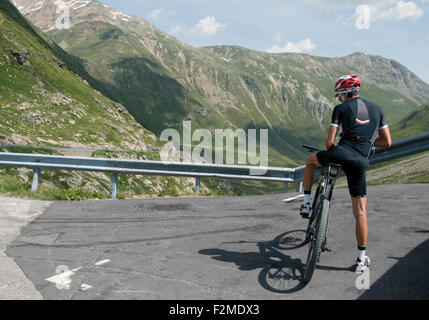 Ciclista a riposo in Passo Forcola, vicino a Livigno, Alpi Italiane Foto Stock