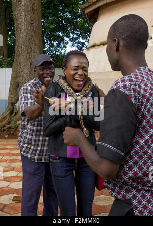 Il Benin, Africa Occidentale, Ouidah, donna urlando come un uomo mette un serpente intorno al collo nel tempio di python Foto Stock