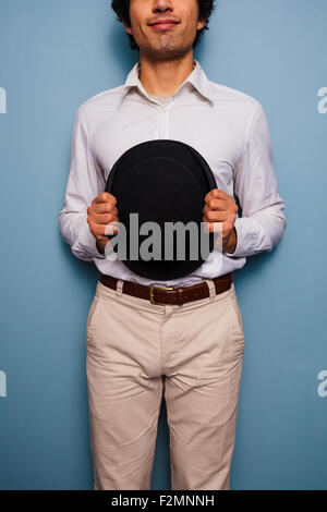 Giovane uomo in piedi da una parete blu con un cappello Foto Stock