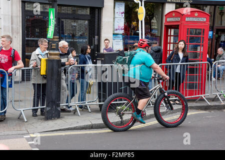 Un grande uomo una corsa in bicicletta attraverso le strade della città di Londra REGNO UNITO Foto Stock