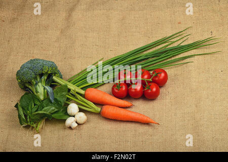 Estate artigianale di verdure e verdi in tela, mazzetto di sei rosso ciliegia matura il pomodoro, raggrinzimento cipolle, due carote, foglie di basilico fresco Foto Stock