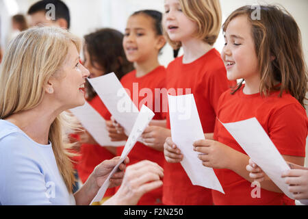 I bambini nel canto del gruppo essendo incoraggiati dall'insegnante Foto Stock