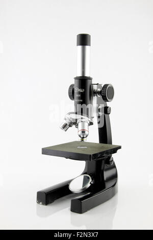 Un vecchio microscopio in aula isolata su una mentre lo sfondo. Foto Stock