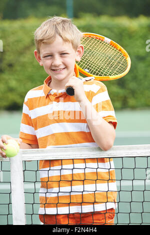 Ritratto di ragazzo giocando a tennis in piedi accanto a Net Foto Stock