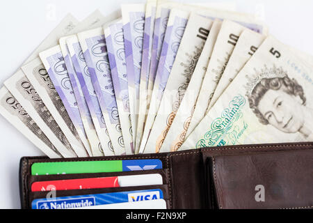 Close up, aperto in pelle marrone portafoglio con spruzzo di Sterlina Inglese banconote a partire da € 5, £10, £20, £50 nonché di plastica le carte di credito. Foto Stock
