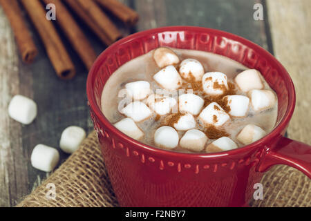 Primo piano della cioccolata calda e Marshmallows con cannella in rosso cup Foto Stock