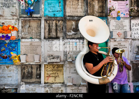 Musicisti messicani gioco accanto a un columbarium durante il giorno dei morti festeggiamenti nel cimitero di Morelia, Messico. Foto Stock