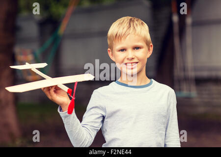 Sorridente ragazzino tenendo un legno modello di aeroplano Foto Stock