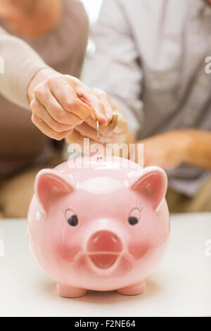 Close up mettendo le mani battere moneta di salvadanaio Foto Stock