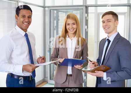 Happy business team nel convenzionale guardando la fotocamera in ufficio Foto Stock