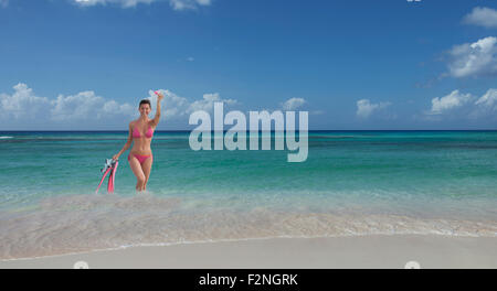 La donna caucasica wading sulla spiaggia con pinne e boccaglio Foto Stock