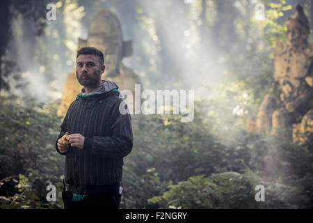 Uomo caucasico esplorare antiche statue in foresta Foto Stock