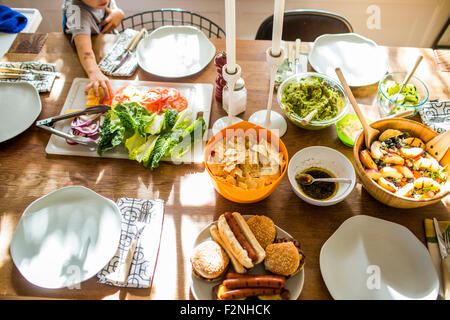 Baby girl raggiungendo per verdure a buffet al tavolo Foto Stock