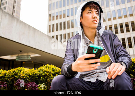 Uomo asiatico utilizzando il cellulare in città Foto Stock