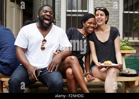 Gli amici di ridere a backyard barbecue Foto Stock