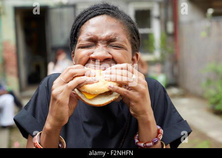 African American donna di mangiare al barbecue nel cortile Foto Stock