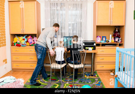 Caucasian padre e figli utilizzando il computer in camera da letto Foto Stock