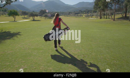 La donna caucasica portando borsa da golf sul corso Foto Stock