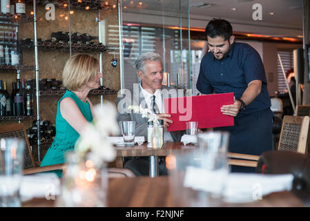 Cameriere assistere giovane con menu al ristorante Foto Stock