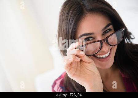 Donna del peering sopra gli occhiali Foto Stock